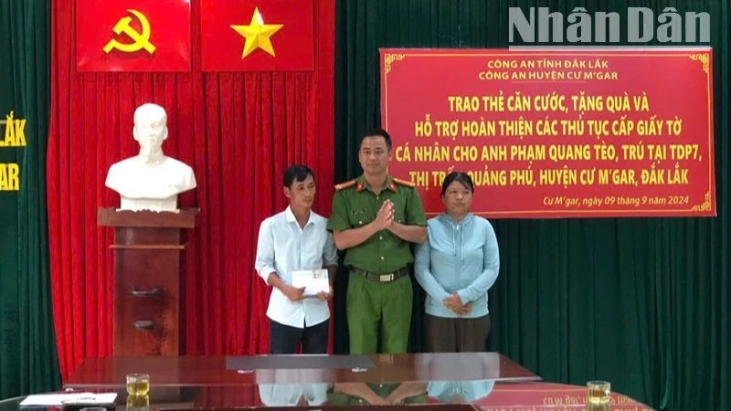 Thượng tá Lê Văn Khánh, Phó Trưởng Công an huyện Cư M'gar trao căn cước công dân và số tiền do cán bộ, chiến sĩ Công an huyện quyên góp tặng cho vợ chồng anh Phạm Quang Tèo.