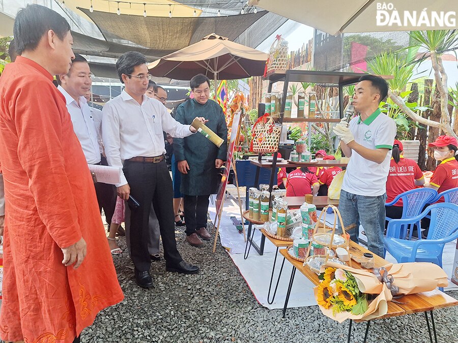 Phó Chủ tịch UBND thành phố Trần Chí Cường (thứ 3, trái sang) tham quan gian hàng chả giò làm trong ống tre. Ảnh: THU HÀ