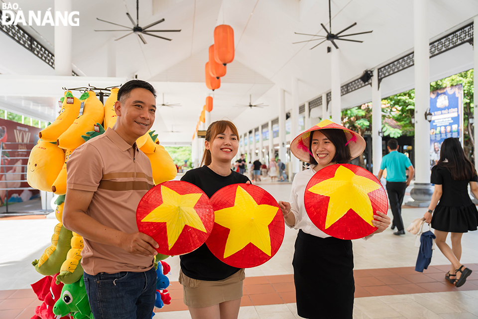 Nhiều du khách thích thú check-in với áo cờ đỏ sao vàng, nón lá được trang trí cờ đỏ sao vàng. Ảnh: THU HÀ.