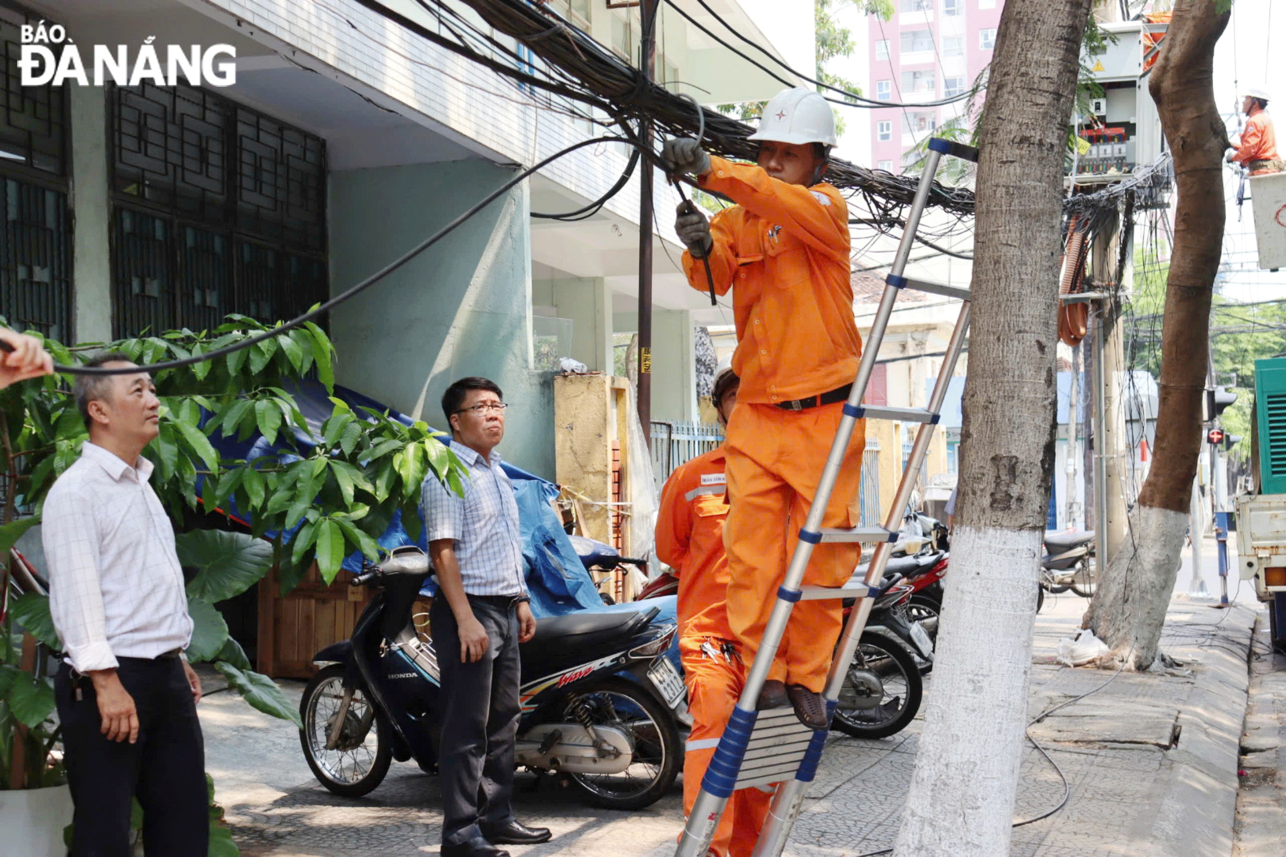 Lực lượng chức năng phối hợp chỉnh trang, sắp xếp cáp viễn thông để bảo đảm mỹ quan đô thị.  Ảnh: TRẦN TRÚC