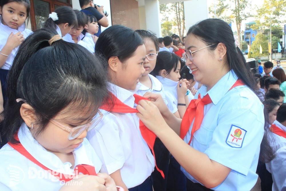 Bí thư Thành đoàn, Chủ tịch Hội đồng Đội thành phố Biên Hòa trao khăn quàng đỏ cho đội viên mới tại lễ kết nạp. Ảnh: Nga Sơn