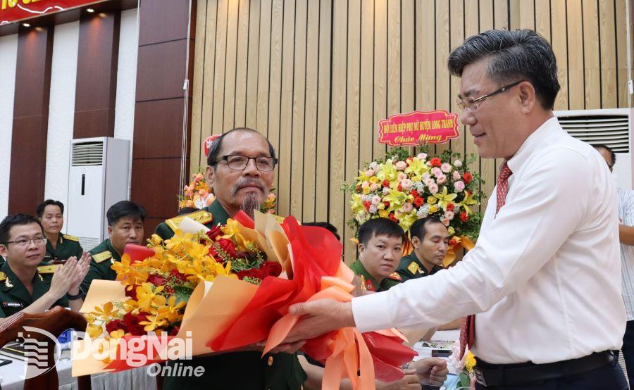 Bí thư Huyện ủy, Bí thư Đảng ủy Quân sự huyện Long Thành tặng hoa Anh hùng Lực lượng vũ trang nhân dân Lương Văn Xuân. Ảnh: Nguyệt Hà