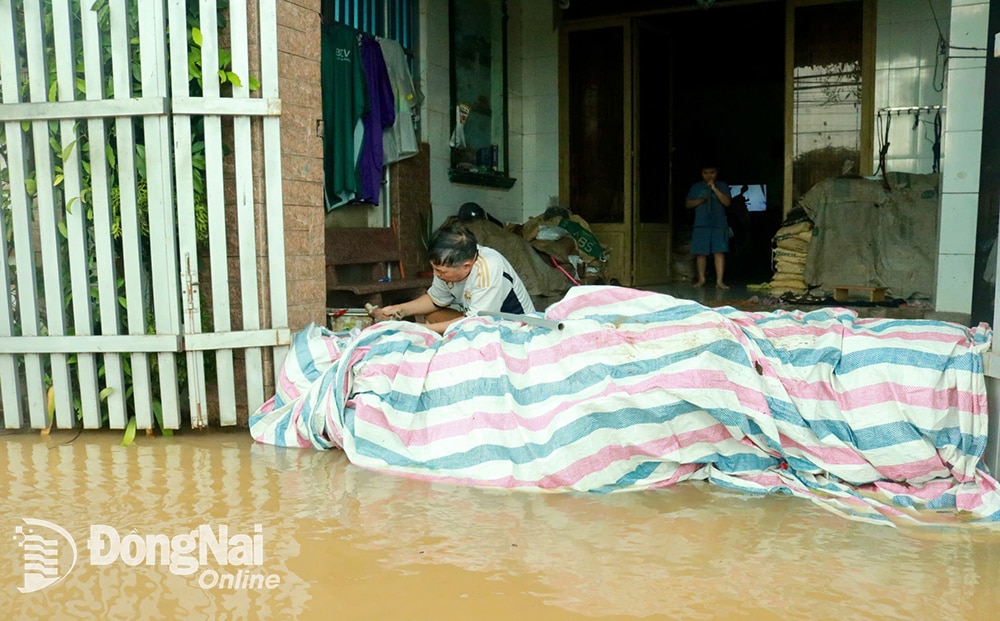 Người dân đắp cát để chống nước tràn vào nhà và sử dụng máy bơm để bơm nước ra ngoài. Ảnh: Minh Hạnh