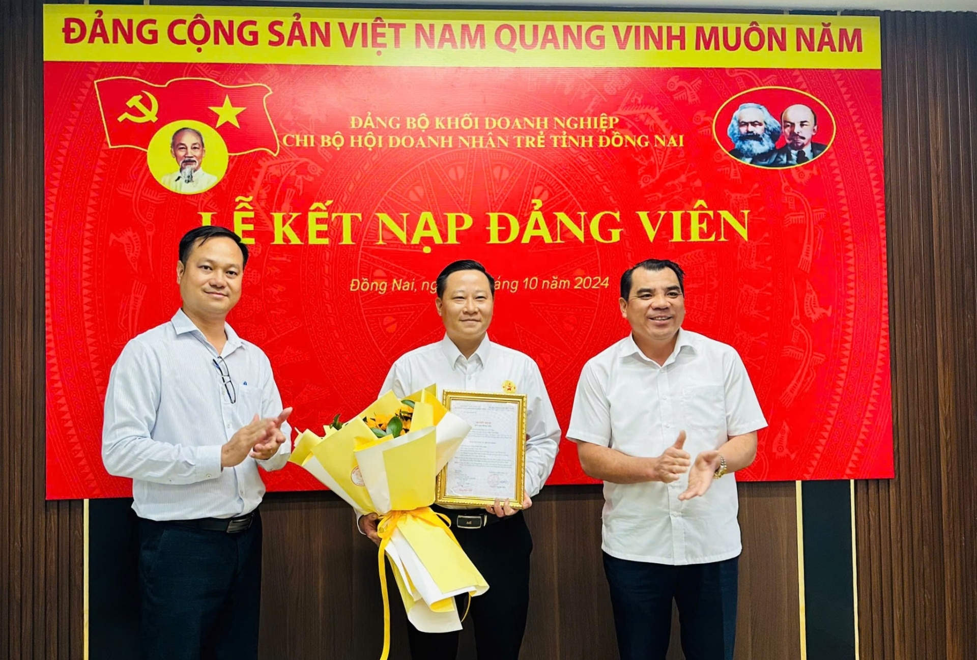 Bí thư Đảng ủy Khối doanh nghiệp Nguyễn Cao Cường (bìa phải) và Bí thư Chi bộ Hội Doanh nhân trẻ Đồng Nai Đặng Quốc Nghi trao chứng nhận kết nạp đảng viên mới cho ông Trần Văn Giáp. Ảnh: Vương Thế