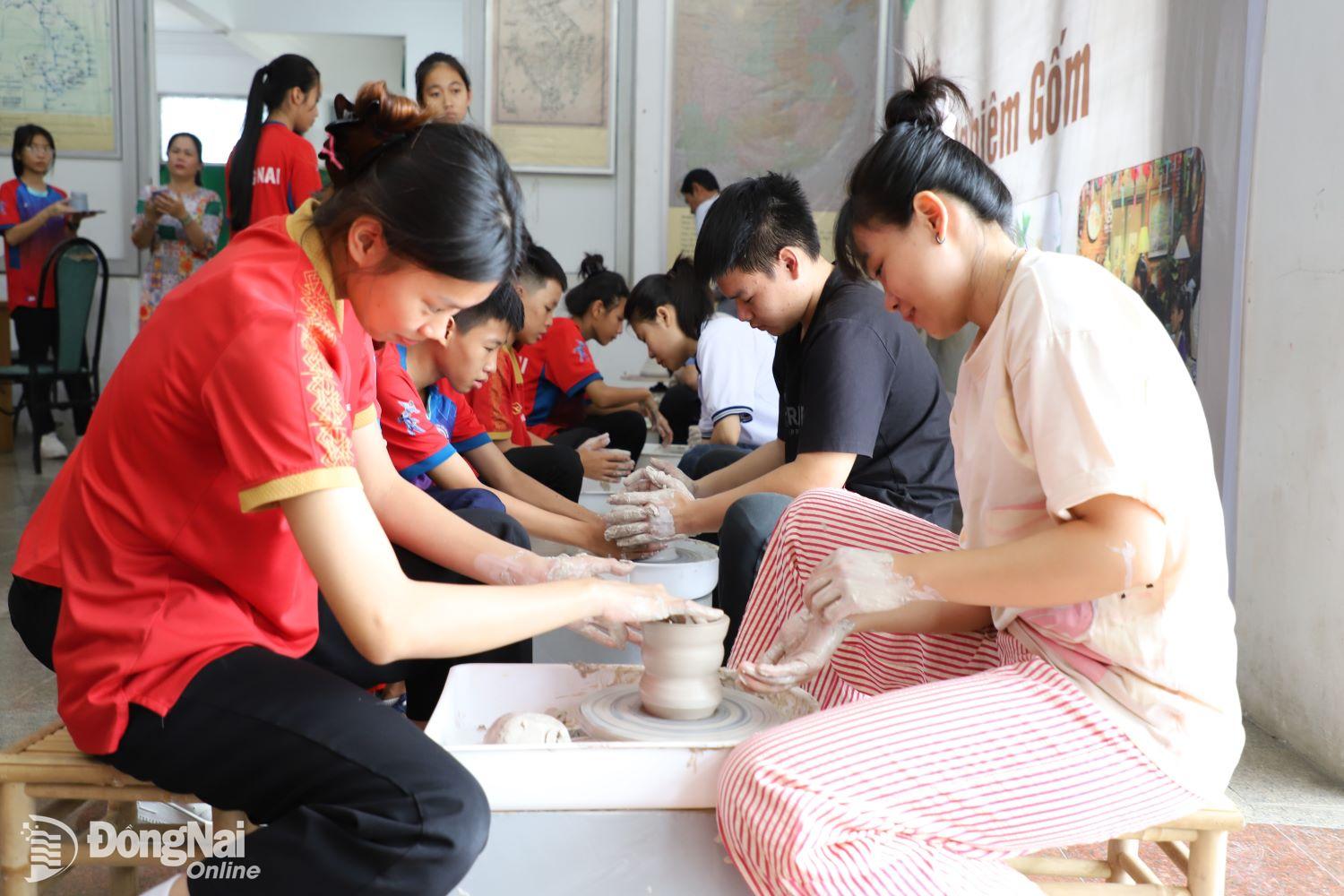 Học sinh, sinh viên Trường cao đẳng Mỹ thuật trang trí Đồng Nai hướng dẫn du khách xoay gốm. Ảnh: My Ny