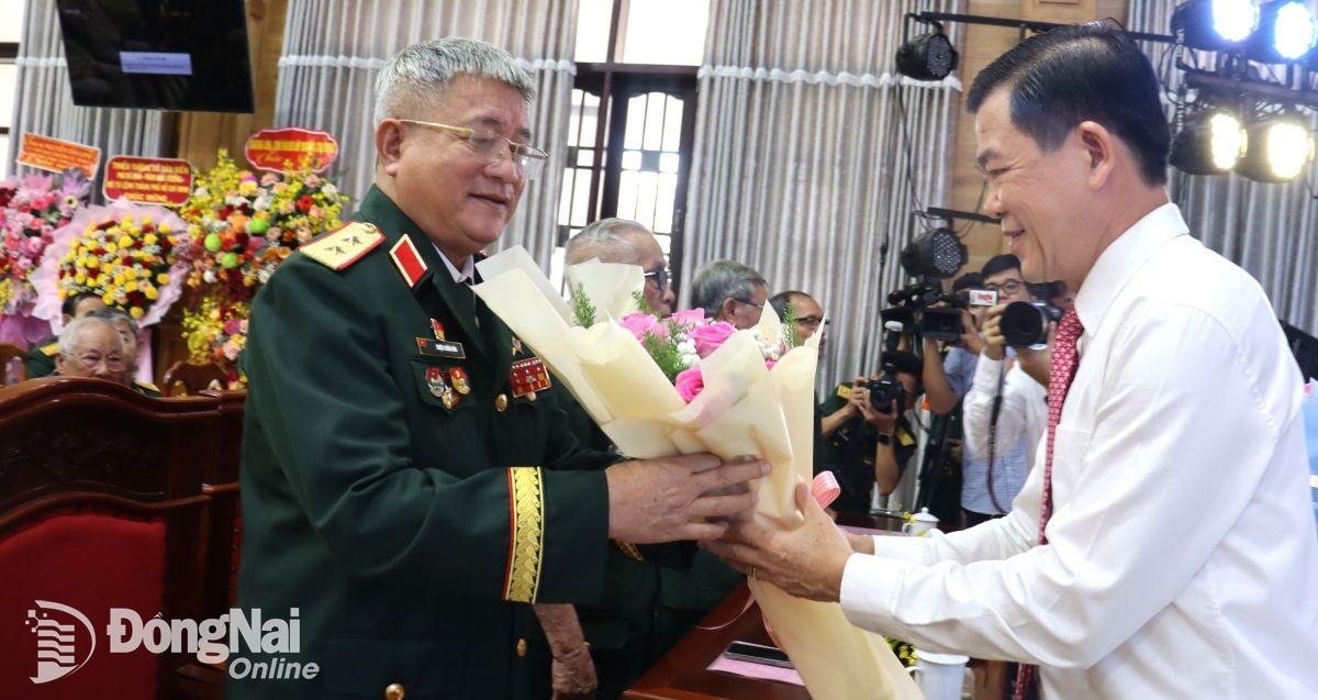 Bí thư Tỉnh ủy Nguyễn Hồng Lĩnh tặng hoa chúc mừng trung tướng, Anh hùng Lực lượng vũ trang nhân dân Triệu Xuân Hòa, nguyên Tư lệnh Quân khu 7. Ảnh: Nguyệt Hà