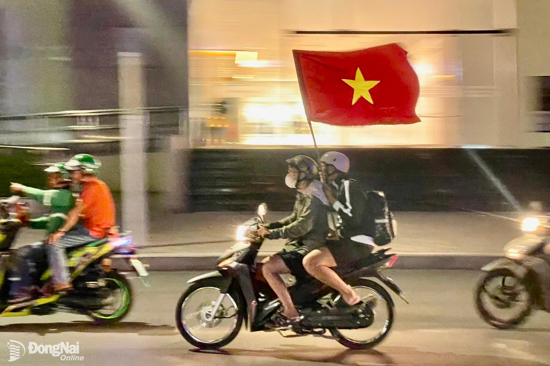 Cờ đỏ sao vàng tung bay trên các tuyến đường của thành phố Biên Hòa khi người dân đổ ra đường ăn mừng chiến thắng của đội tuyển bóng đá Việt Nam. Ảnh: Lê Duy