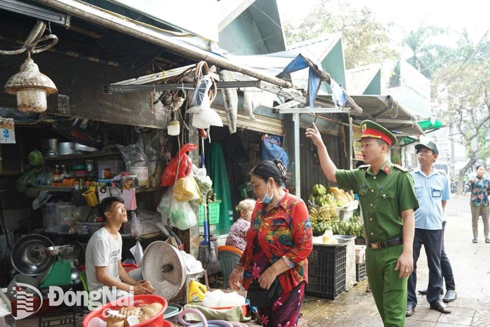 Công an phường Quang Vinh nhắc nhở các tiểu thương thu dọn mái bạt trên đường Nguyễn Văn Trị. Ảnh: Lê Duy