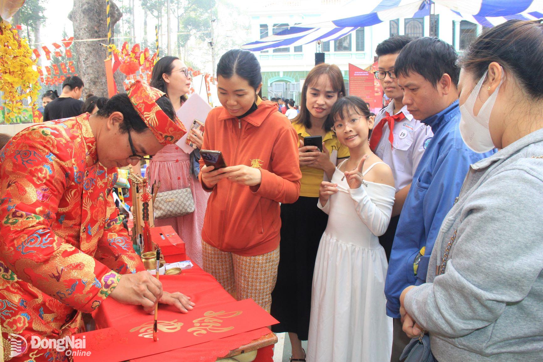 Các em thiếu nhi và phụ huynh xin chữ tại gian hàng thư pháp. Ảnh: Nga Sơn