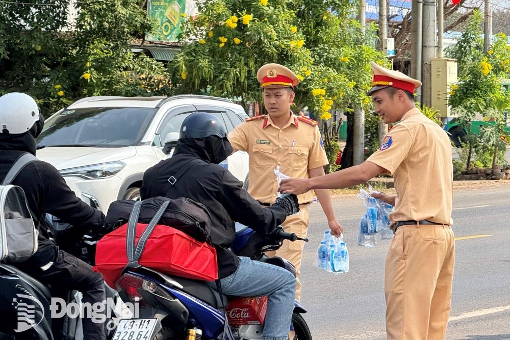 Đội Cảnh sát giao thông số 2 (Phòng Cảnh sát giao thông Công an tỉnh) phát nước suối cho người dân di chuyển trên quốc lộ 20 về quê. Ảnh: Đăng Tùng