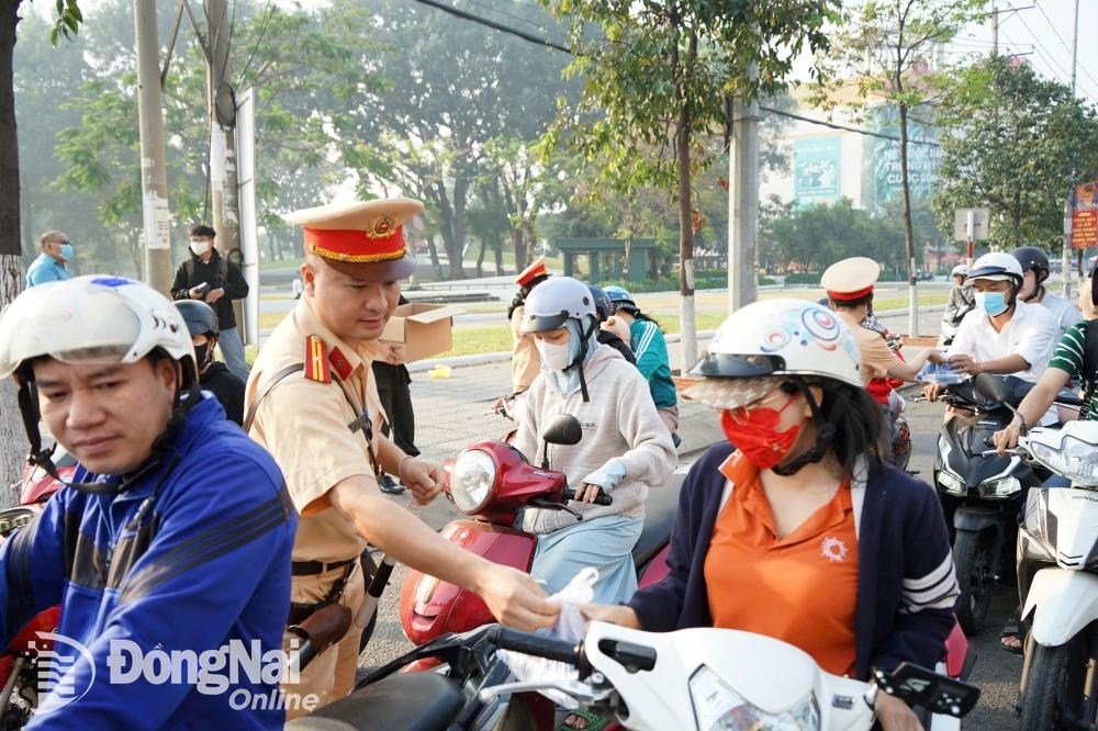 Đội Đăng ký, quản lý phương tiện (Phòng Cảnh sát giao thông Công an tỉnh) phát nước suối, khăn lạnh cho người dân di chuyển trên quốc lộ 1 (ngã tư Amata, thành phố Biên Hòa) về quê đón Tết. Ảnh: Lê Duy