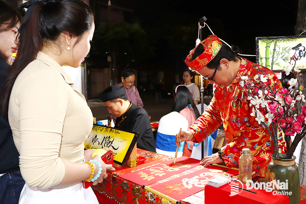 Viết thư pháp tặng chữ cho du khách tại Không gian Văn hóa - ẩm thực Biên Hòa. Ảnh: N.Liên