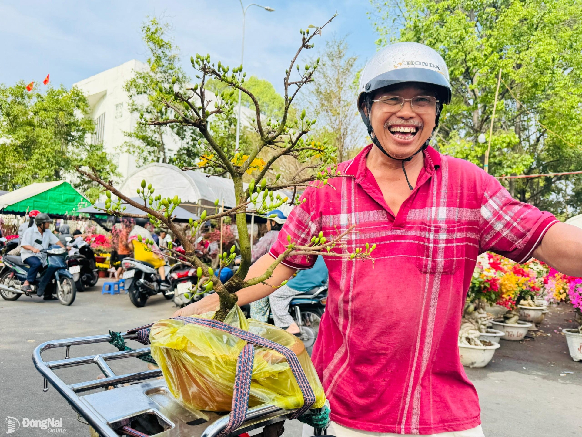 Người đàn ông tươi cười rạng rỡ khi mua được cây mai giá 200 ngàn đồng rất ưng ý. Ảnh: Hạnh Dung