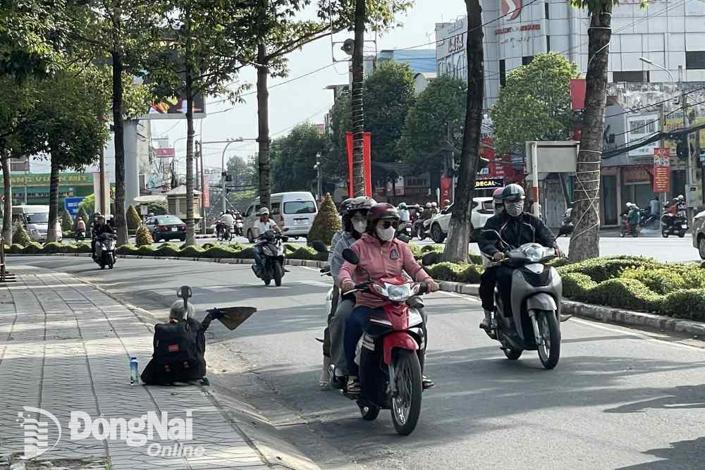 Người lang thang, ăn xin xin tiền người dân chờ đèn đỏ trên đường Nguyễn Ái Quốc (phường Tân Phong). Ảnh Lê Duy