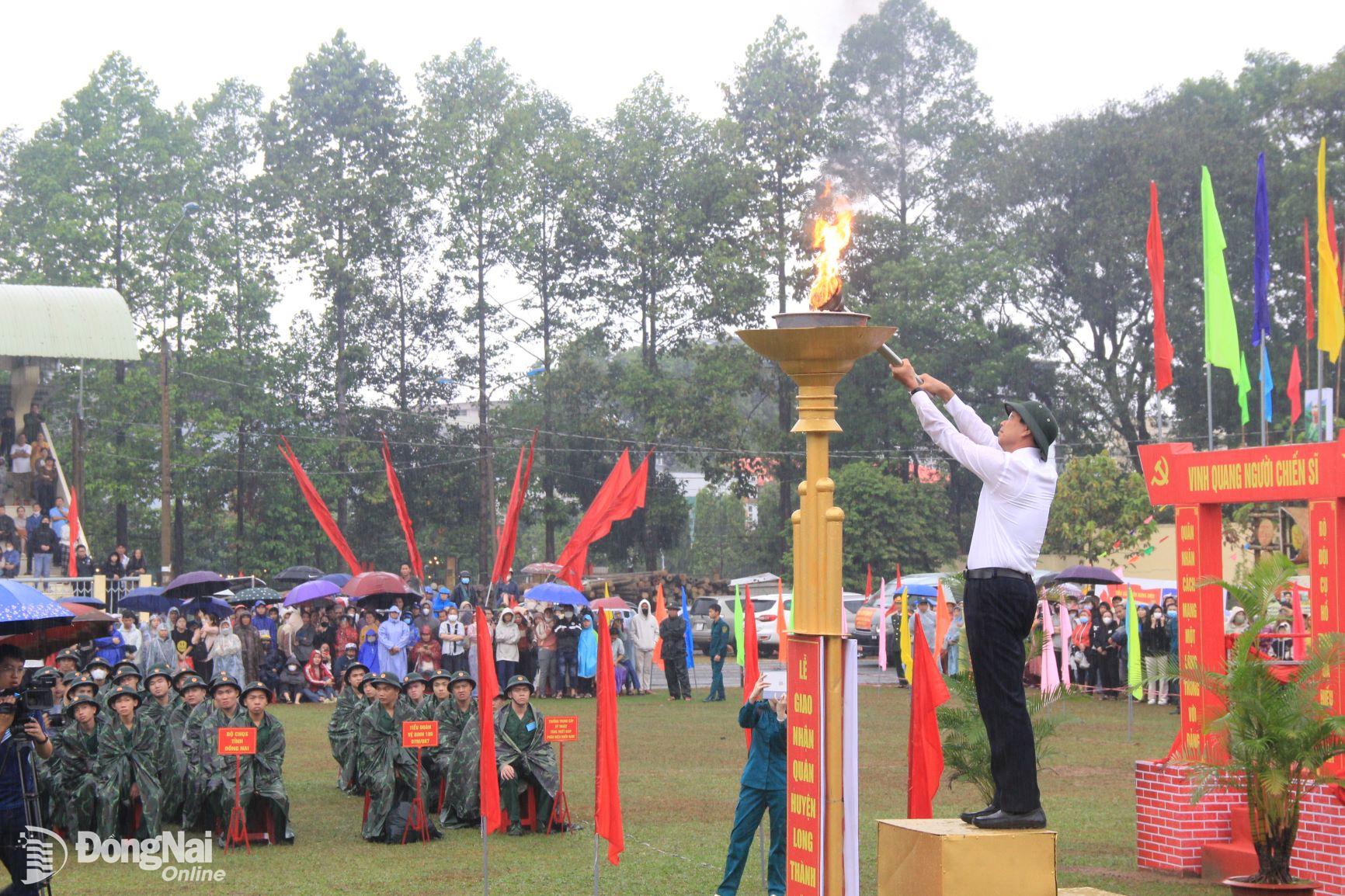 Bí thư Huyện ủy Long Thành Võ Văn Phi thực hiện nghi thức đốt đuốc truyền thống tại lễ giao, nhận quân. Ảnh: Nga Sơn