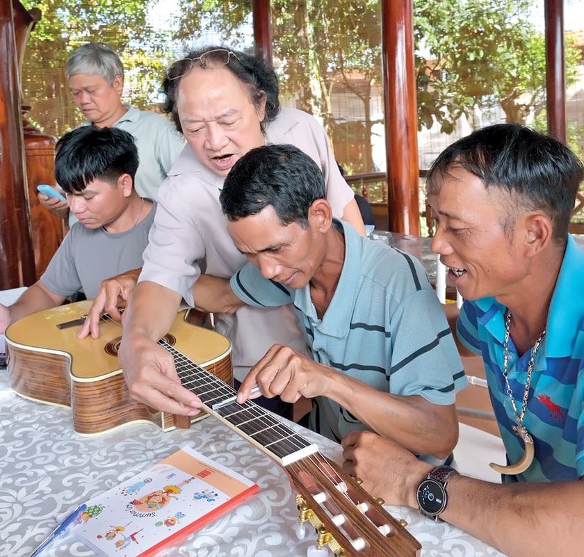 Các chuyên gia dùng đàn guitar làm thước để hướng dẫn nghệ nhân cách đo thang âm cồng chiêng. Ảnh: H.N