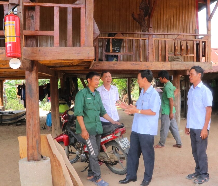 Anh Đinh Lech (bìa trái ở làng Quel, xã Sró, huyện Kông Chro) chia sẻ niềm vui được huyện hỗ trợ kinh phí xây nhà ở khang trang. Ảnh: Ngọc Minh