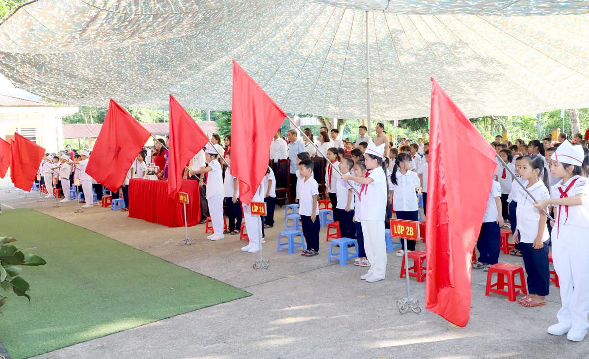 Các đại biểu, thầy – cô giáo và các em học sinh thực hiện nghi thức chào cờ.
