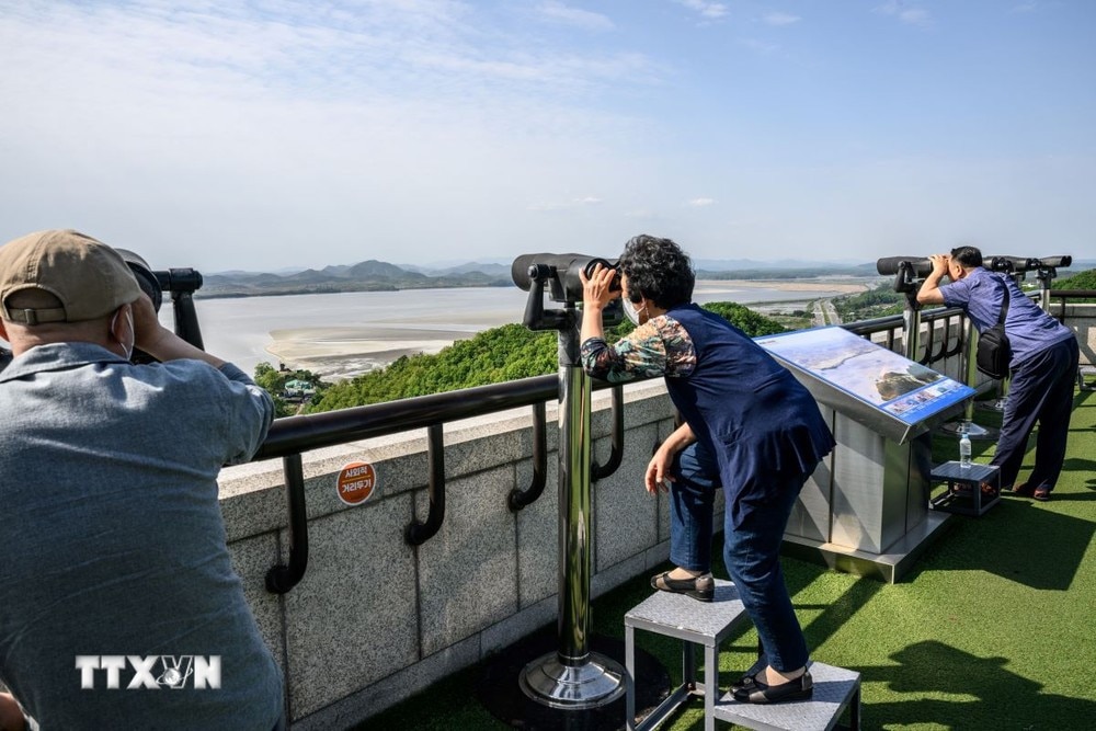 Khách du lịch quan sát bằng ống nhòm Khu phi quân sự (DMZ) liên Triều từ Đài quan sát Odusan ở Paju, Hàn Quốc, ngày 12/5/2022. (Ảnh: AFP/TTXVN)