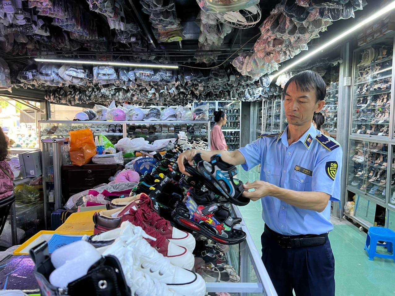 Cán bộ Đội Quản lý thị trường số 2 kiểm tra hàng hóa tại một cơ sở kinh doanh giày dép ở Vạn Ninh