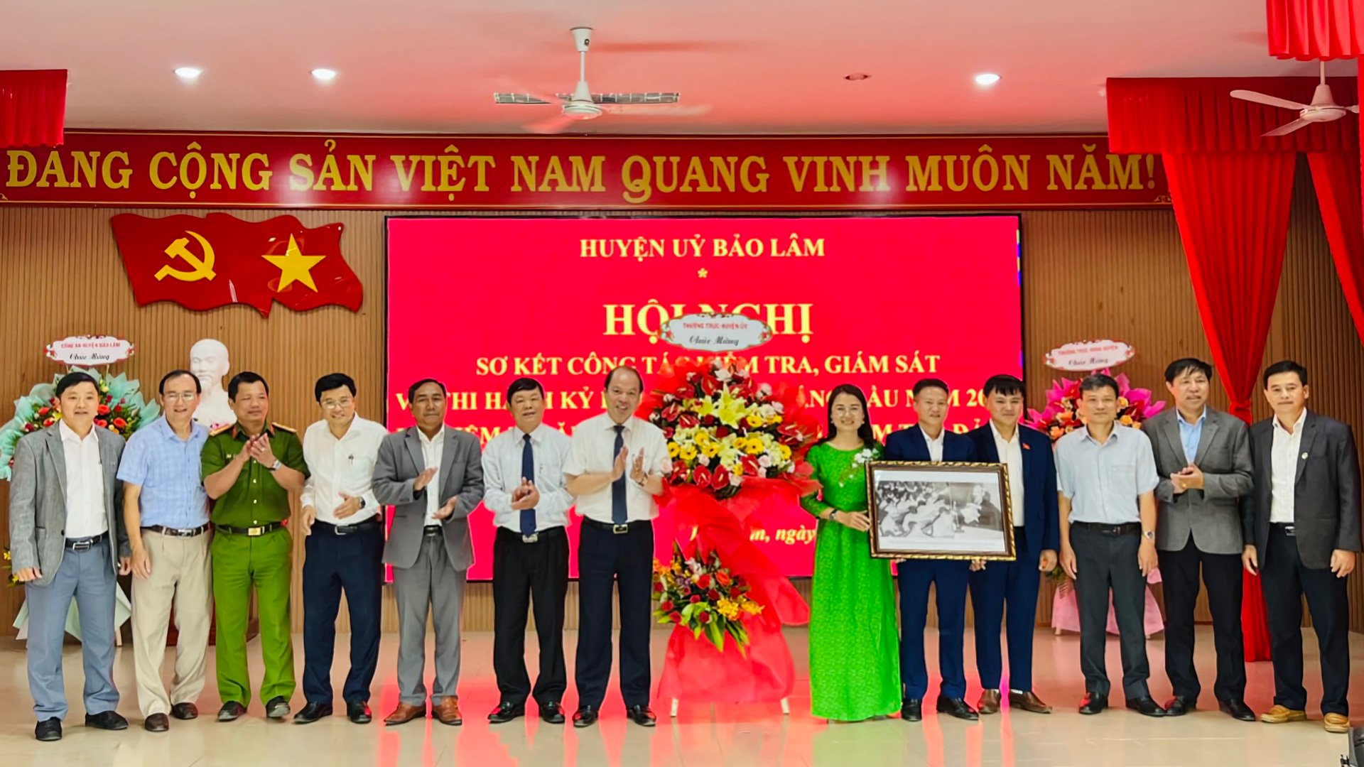 Lãnh đạo huyện tặng hoa và bức tranh Chủ tịch Hồ Chí Minh nói chuyện tại Hội nghị tổng kết công tác kiểm tra