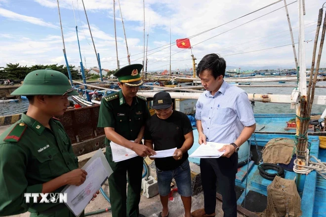 Lực lượng Bộ đội Biên phòng tuyên truyền vận động ngư dân khai thác thủy sản theo quy định của pháp luật, trước khi ra khơi ở cảng cá huyện Hoài Nhơn, tỉnh Bình Định. (Ảnh: Vũ Sinh/TTXVN)