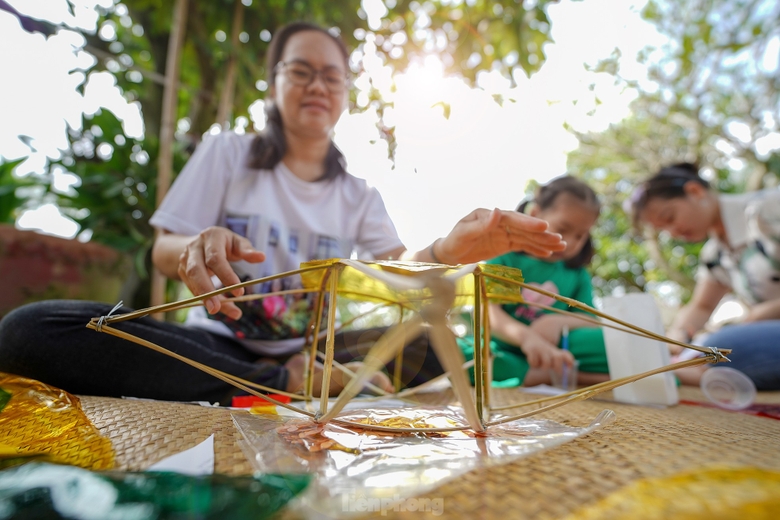 "Công đoạn nào khó thì người lớn sẽ làm phụ các con. Mấy bé thích cầm cọ quét keo và dán giấy kính. Hoạt động này cũng một phần giáo dục các bé về nét văn hóa mà ngày nay ít thấy nữa khi lồng đèn gắn pin, phát nhạc bán đại trà. Chiếc đèn ông sao truyền thống có hình sao vàng năm cánh. Đây cũng là hình ảnh quen thuộc chúng ta vẫn thường thấy trên lá quốc kỳ", chị Hồng Nhung (áo trắng) chia sẻ. ảnh 7