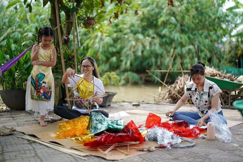 "Công đoạn nào khó thì người lớn sẽ làm phụ các con. Mấy bé thích cầm cọ quét keo và dán giấy kính. Hoạt động này cũng một phần giáo dục các bé về nét văn hóa mà ngày nay ít thấy nữa khi lồng đèn gắn pin, phát nhạc bán đại trà. Chiếc đèn ông sao truyền thống có hình sao vàng năm cánh. Đây cũng là hình ảnh quen thuộc chúng ta vẫn thường thấy trên lá quốc kỳ", chị Hồng Nhung (áo trắng) chia sẻ. ảnh 5