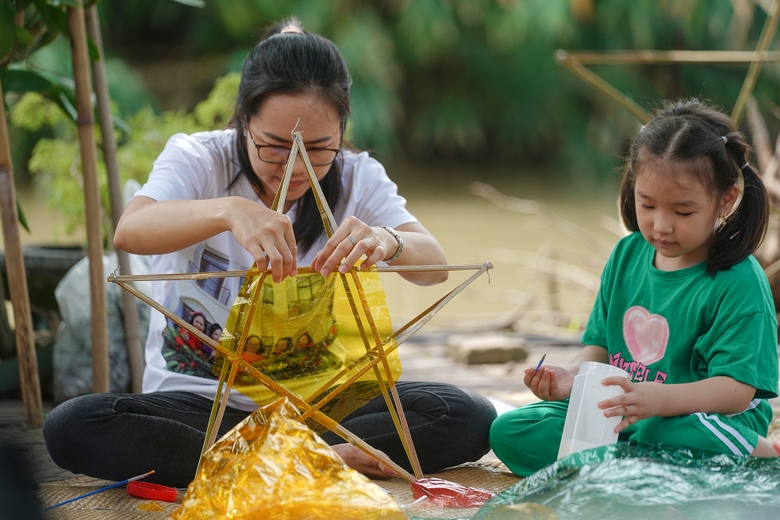 "Công đoạn nào khó thì người lớn sẽ làm phụ các con. Mấy bé thích cầm cọ quét keo và dán giấy kính. Hoạt động này cũng một phần giáo dục các bé về nét văn hóa mà ngày nay ít thấy nữa khi lồng đèn gắn pin, phát nhạc bán đại trà. Chiếc đèn ông sao truyền thống có hình sao vàng năm cánh. Đây cũng là hình ảnh quen thuộc chúng ta vẫn thường thấy trên lá quốc kỳ", chị Hồng Nhung (áo trắng) chia sẻ. ảnh 8