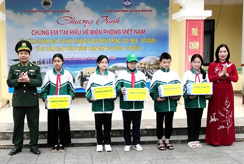 Thượng tá Ngô Văn Bình, Phó Chủ nhiệm Chính trị BĐBP tỉnh và lãnh đạo trường THCS Đồng Phú (TP. Đồng Hới) trao quà động viên học sinh có thành tích cao trong học tập.