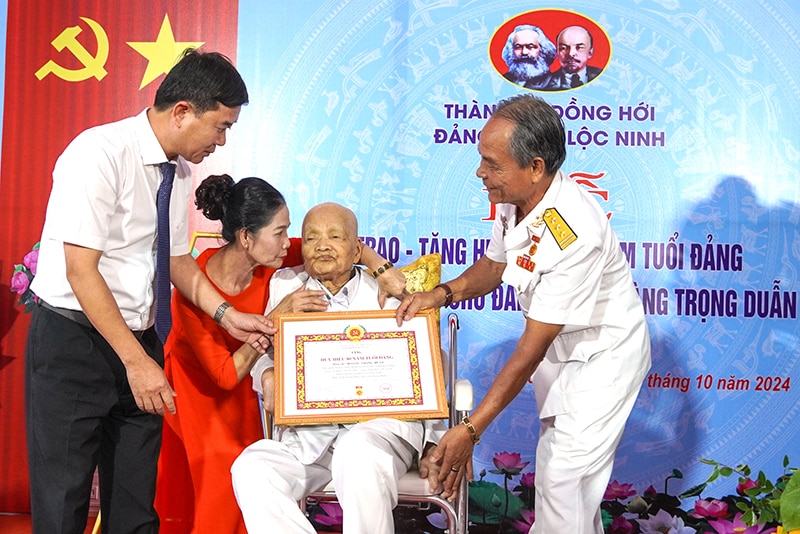 Đại diện Thường trực Thành ủy Đồng Hới gắn Huy hiệu 80 năm tuổi Đảng, trao chứng nhận cho đồng chí đồng chí Hoàng Trọng Duẫn.