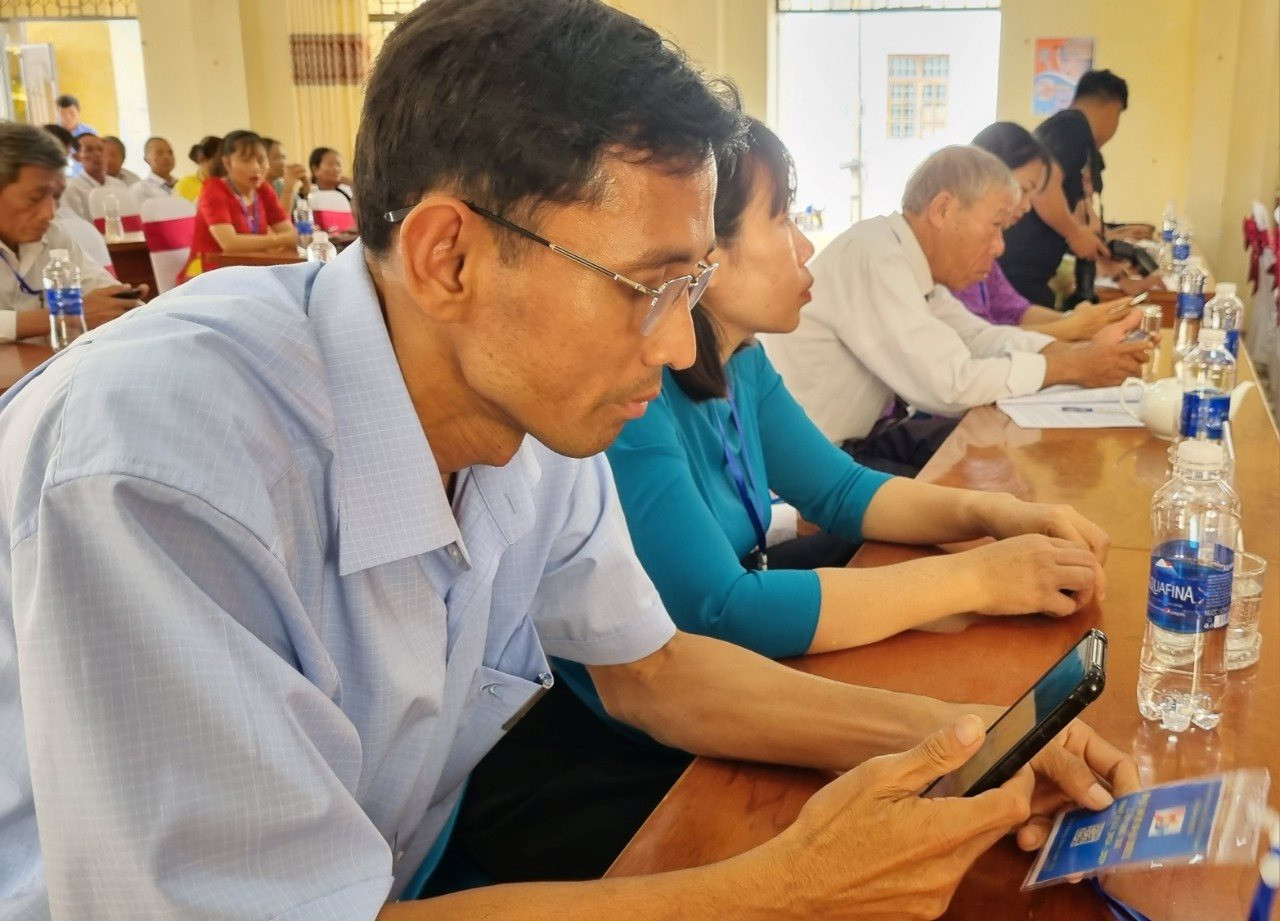 Delegates attending the 12th Congress of the Vietnam Fatherland Front of Binh Duong commune (term 2024 - 2029) scan the QR code to update the Congress documents. Photo: T.N