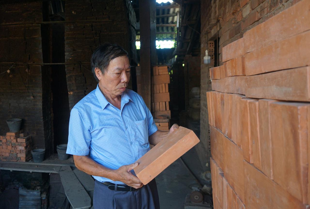 Foto 1. El Sr. Nguyen Qua junto al horno con productos de ladrillo para restauración. Fotografía de Nguyen Van Tho