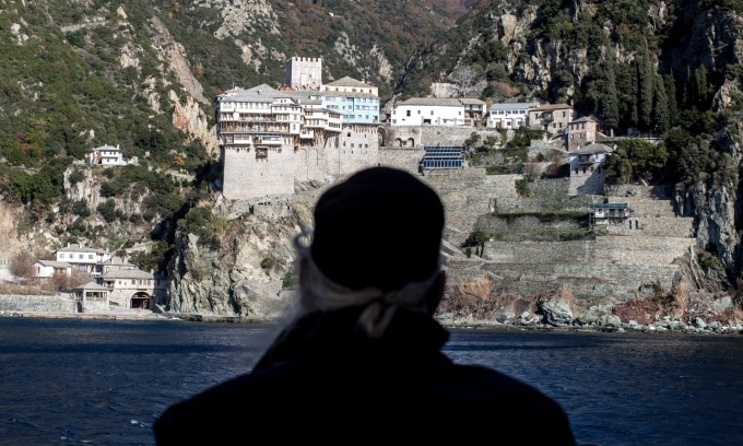 Một thầy tu đứng trên phà nhìn về phía tu viện Dionysiou, một trong 20 tu viện tại vùng núi Athos, miền bắc Hy Lạp. Ảnh: Guardian