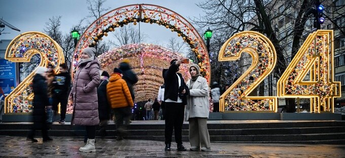 Pedestrians pose in front of a New Year 2024 numerals decoration in central Moscow on December 31, 2023, on the eve of the New Year. (AFP).jpg