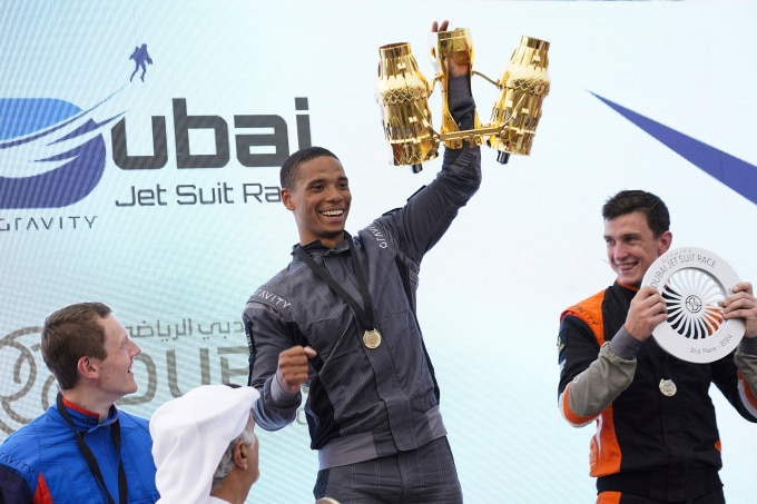 Issa Kalfon, phi công người Anh (giữa), vẫy cúp sau khi chiến thắng trong cuộc đua trang phục phản lực ở Dubai ngày 28/2. Ảnh: AP