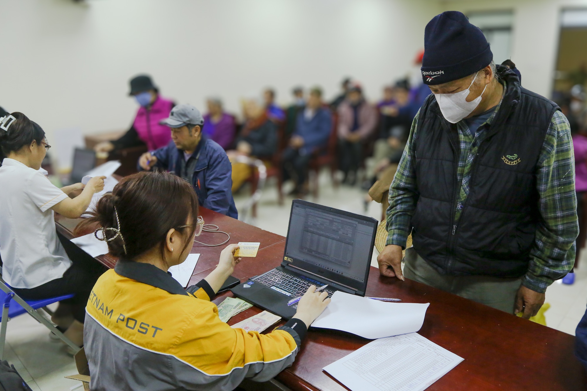 Cán bộ ngành bưu điện phối hợp với ngành bảo hiểm xã hội chi trả lương hưu tại một điểm chi trả ở Hà Nội - Ảnh: HÀ QUÂN