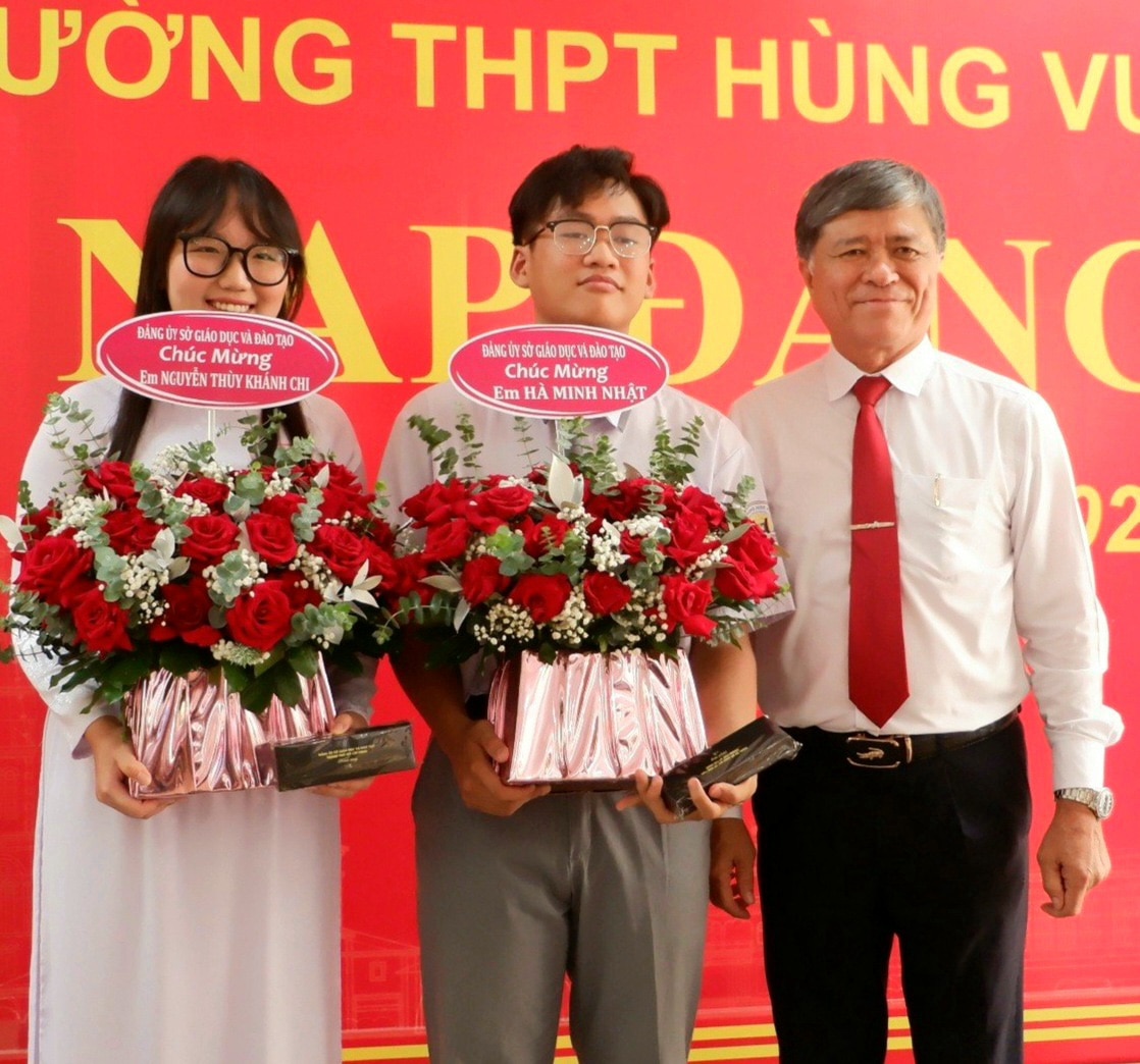 Ông Nguyễn Văn Hiếu, giám đốc Sở Giáo dục và Đào tạo TP.HCM, tặng hoa chúc mừng hai học sinh Hà Minh Nhật (giữa) và Nguyễn Thùy Khánh Chi - Ảnh: KIM ANH